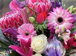 A bright, vibrant floral arrangement, full of pink, red and purple flowers