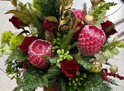 Deep reds, greens and gold in a holiday-themed floral bouquet